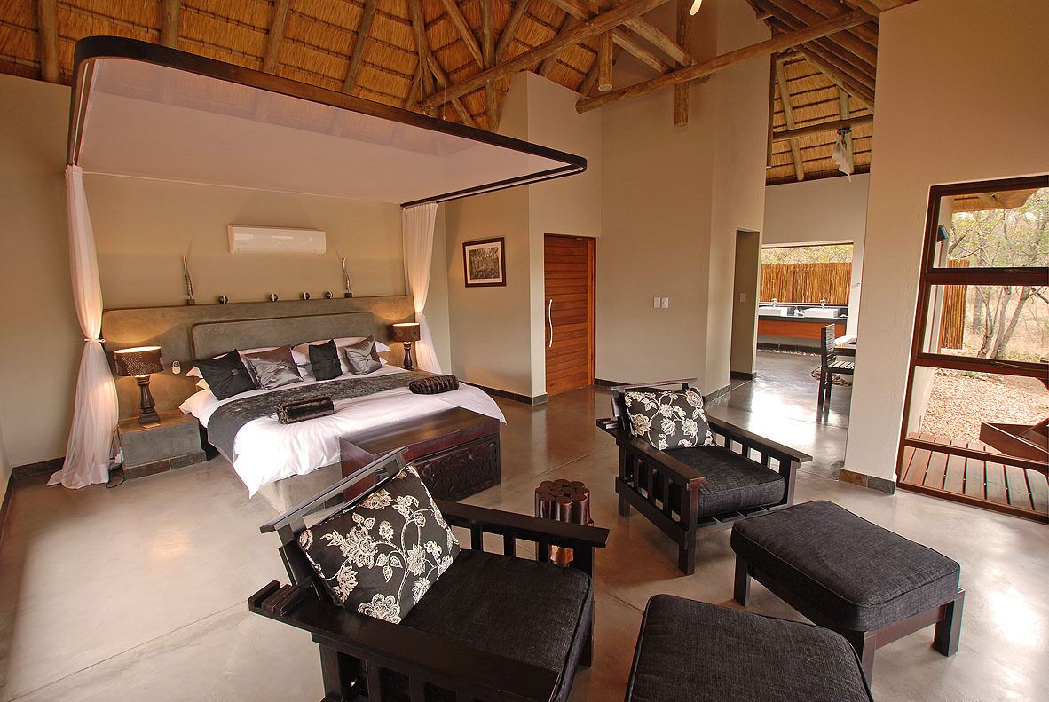 A spacious bedroom with a large bed, bedside tables, a canopy bed, and a view of the outdoor area.