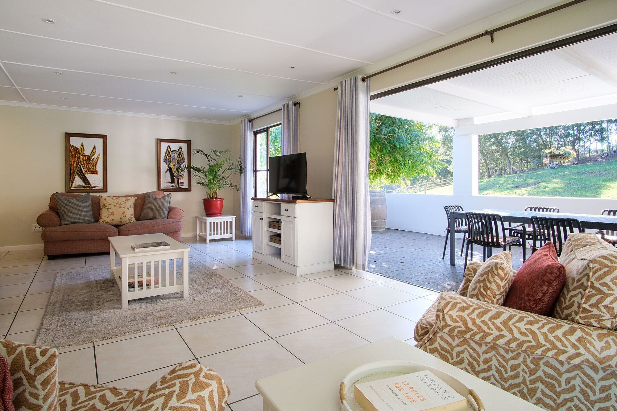 A living room with a sofa, a coffee table, a TV, and a dining area with chairs and a table.