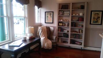 A cozy reading nook with a chair, a bookshelf, and a desk with a lamp.