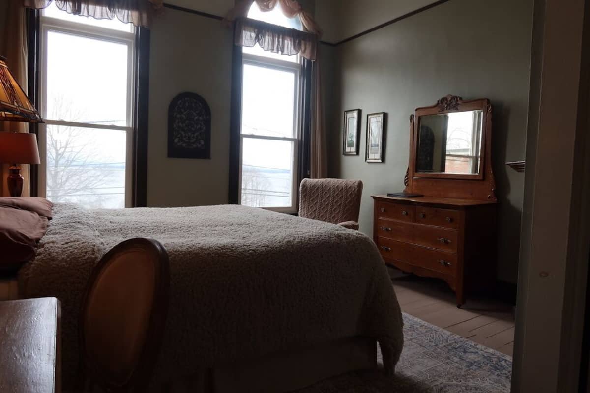 A bedroom with a large bed, a dresser, a chair, and a window with curtains.