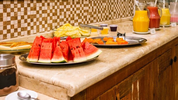 A buffet counter with various fruits, juices, and breakfast items. - Hotel Villa Rebellato (Olímpia)