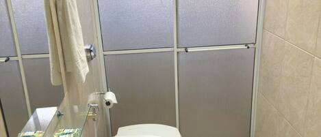 Une salle de bain avec une douche à parois de verre, un lavabo blanc et des toilettes.