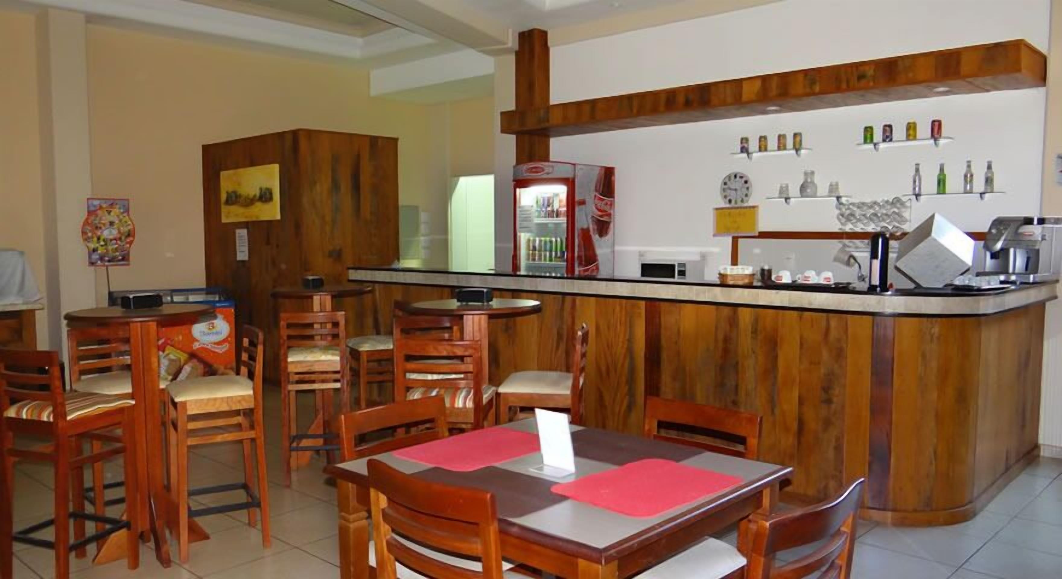 A restaurant with wooden furniture, a bar area, and various kitchen appliances.