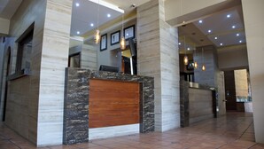 A reception area with a marble reception desk, framed pictures on the wall, and hanging pendant lights. - Hotel Hacienda del Sol (Tonalá)
