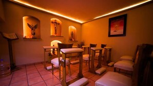 A chapel with wooden benches and chairs, a piano, and religious statues. - Hotel Hacienda del Sol (Tonalá)