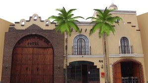 A historic building with a large wooden entrance, palm trees, and a dome on the roof. - Hotel Hacienda del Sol (Tonalá)