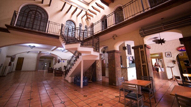 A spacious interior with a high ceiling, a central staircase, and multiple balconies. - Hotel Hacienda del Sol (Tonalá)