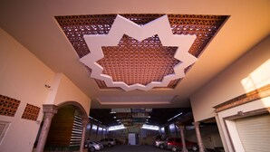 An interior view of a parking garage with a distinctive geometric ceiling design, multiple parking spaces, and a central entrance. - Hotel Hacienda del Sol (Tonalá)
