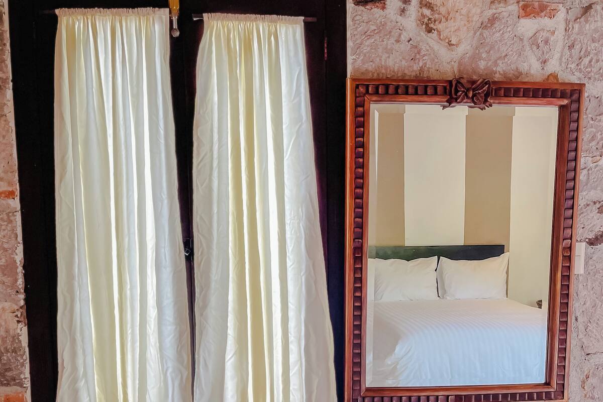 Une chambre avec un lit, un miroir et une commode.