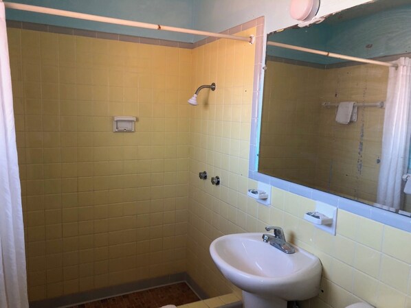 Un baño pequeño con azulejos amarillos, un lavabo blanco y un espejo encima.