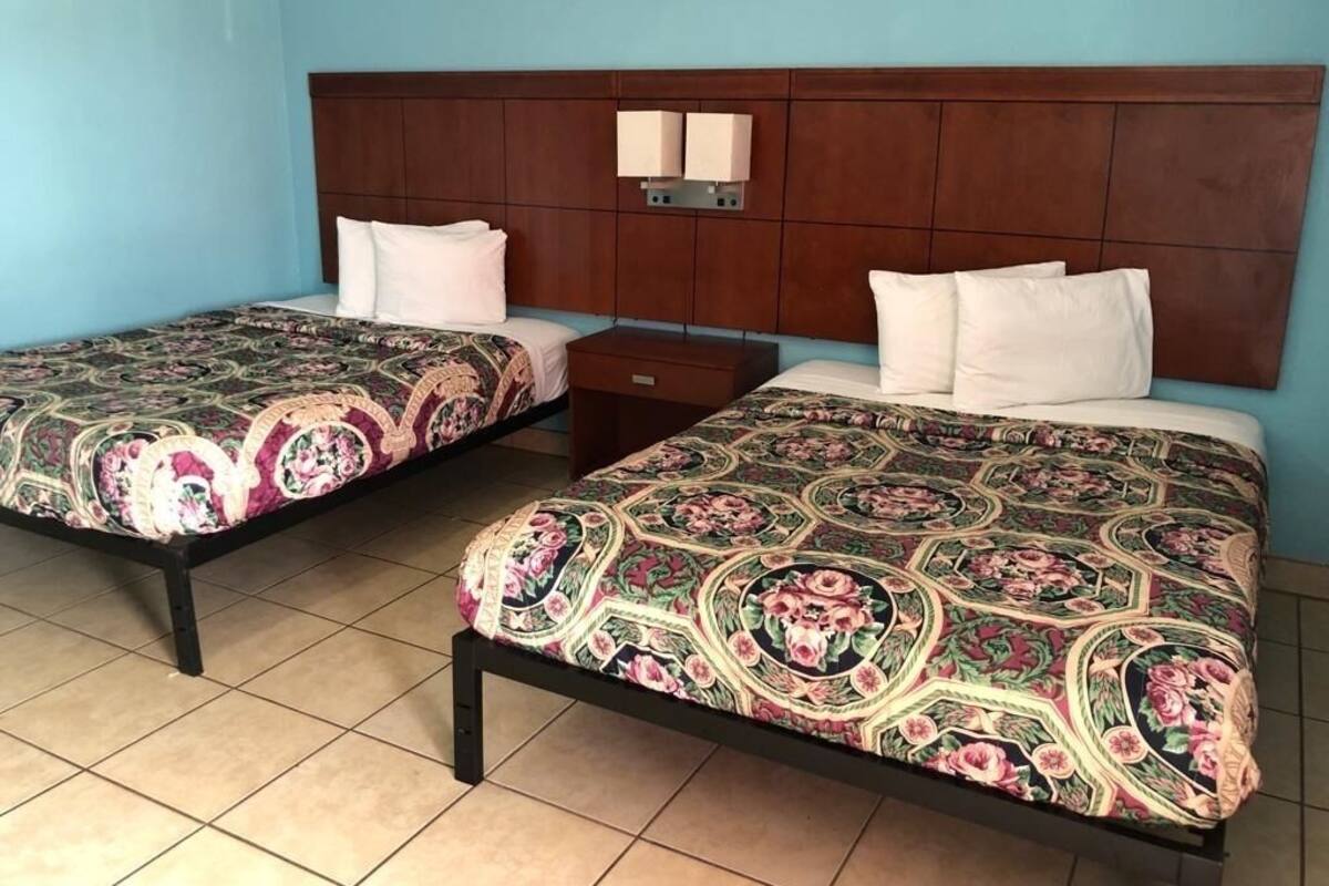 Two single beds with floral-patterned bedding, a wooden headboard, and bedside lamps.