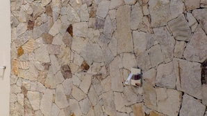 Un muro di pietra con una grata metallica e un piccolo dispositivo fissato.