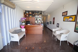 A reception area with a wooden desk, white wicker chairs, and a decorative wall with framed artwork.
