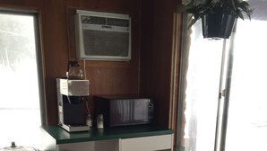 A compact room with a kitchenette, a microwave, a coffee maker, a small trash bin, and a red sofa. - Crown Inn (Toledo)