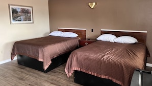 A hotel room with two beds, wooden headboards, and a painting on the wall. - Crown Inn (Toledo)