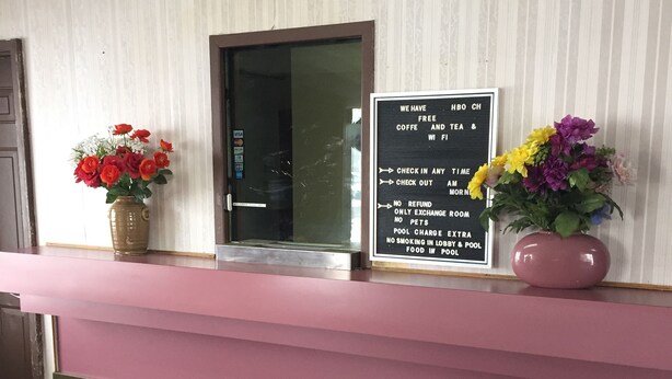 A reception desk with a sign detailing amenities like free HBO, coffee, tea, and Wi-Fi. - Crown Inn (Toledo)