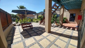 A patio area with a wooden bench, a large umbrella, and a staircase leading to an upper level.