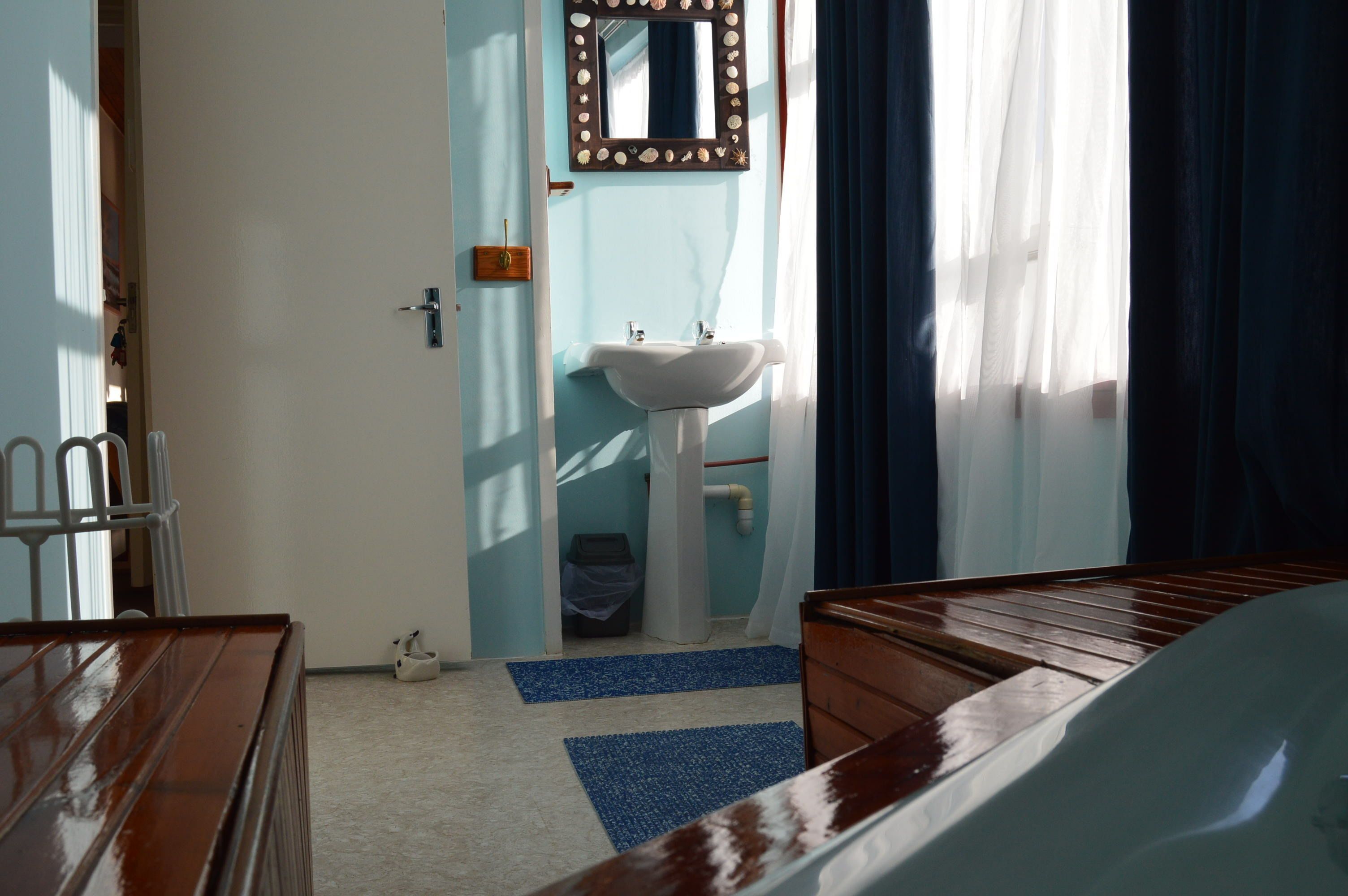 A room with a wooden bed, a white sink, and a mirror.