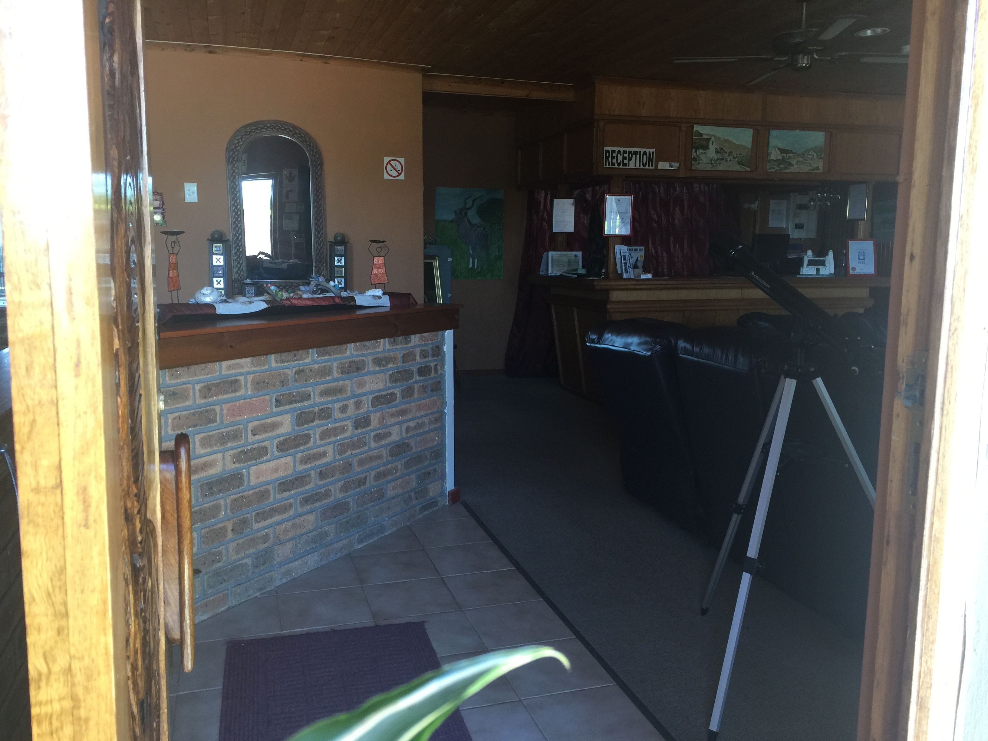 A reception area with a brick counter, a mirror, and a 'Reception' sign.