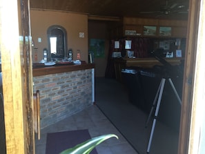 A reception area with a brick counter, a mirror, and a 'Reception' sign. - Fisherhaven Traveller's Lodge - Hostel (Hermanus)