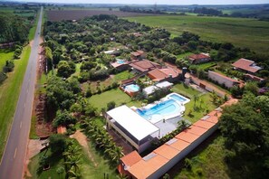 An aerial view of a residential area with houses, a swimming pool, and a road. - Divino Canto Pousada (Olimpia)