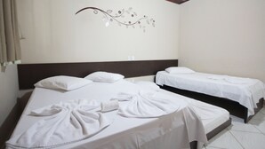 Habitació d'hotel amb dos llits, roba de llit blanca, un element decoratiu a la paret i un sostre de fusta.