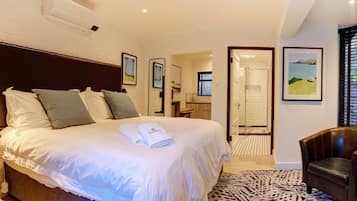 Ein Hotelzimmer mit einem großen Bett, einem Badezimmer mit Dusche und einem Sessel.