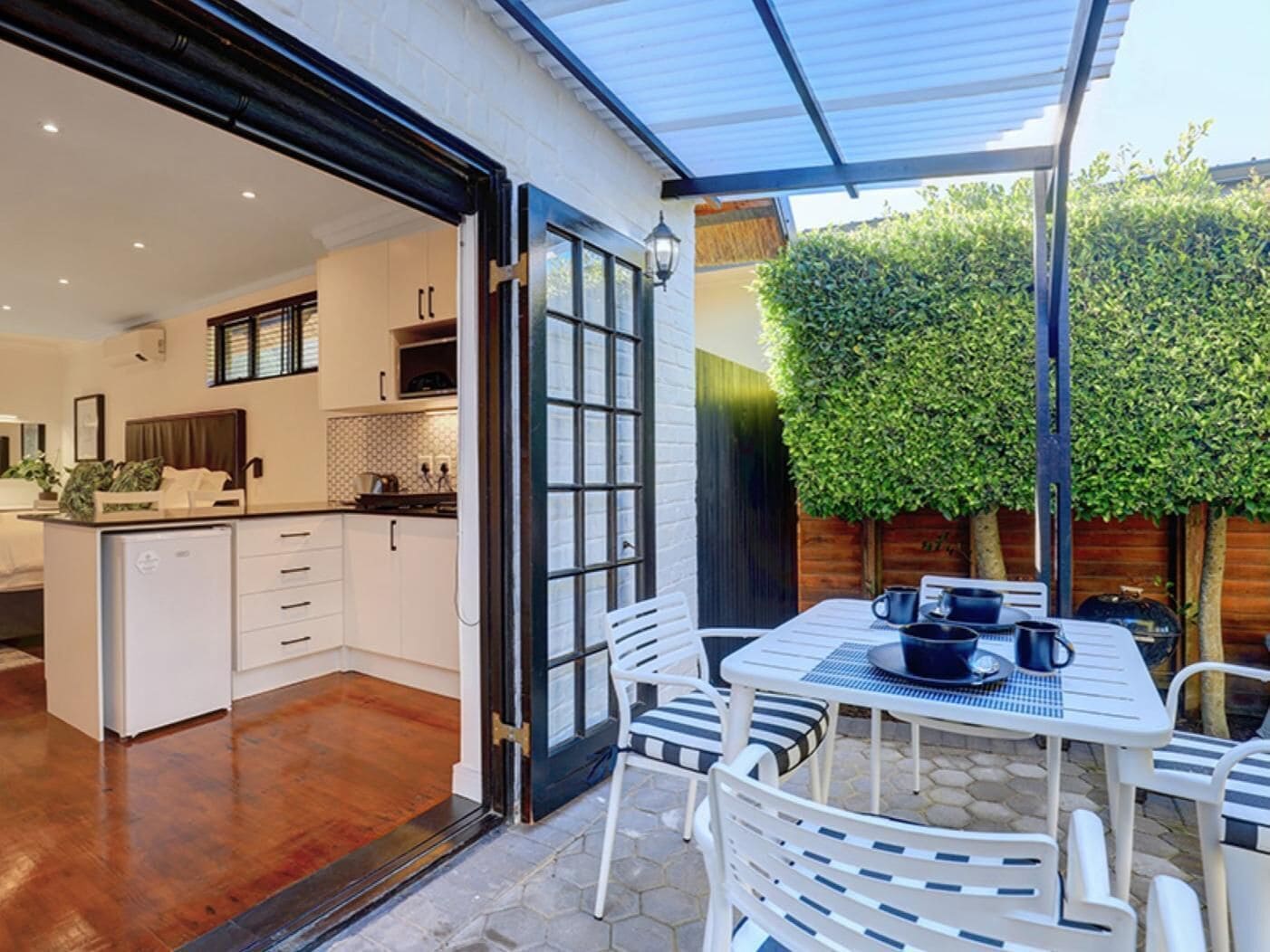 A modern kitchen with white cabinets, a dining area with a table and chairs, and a large window.