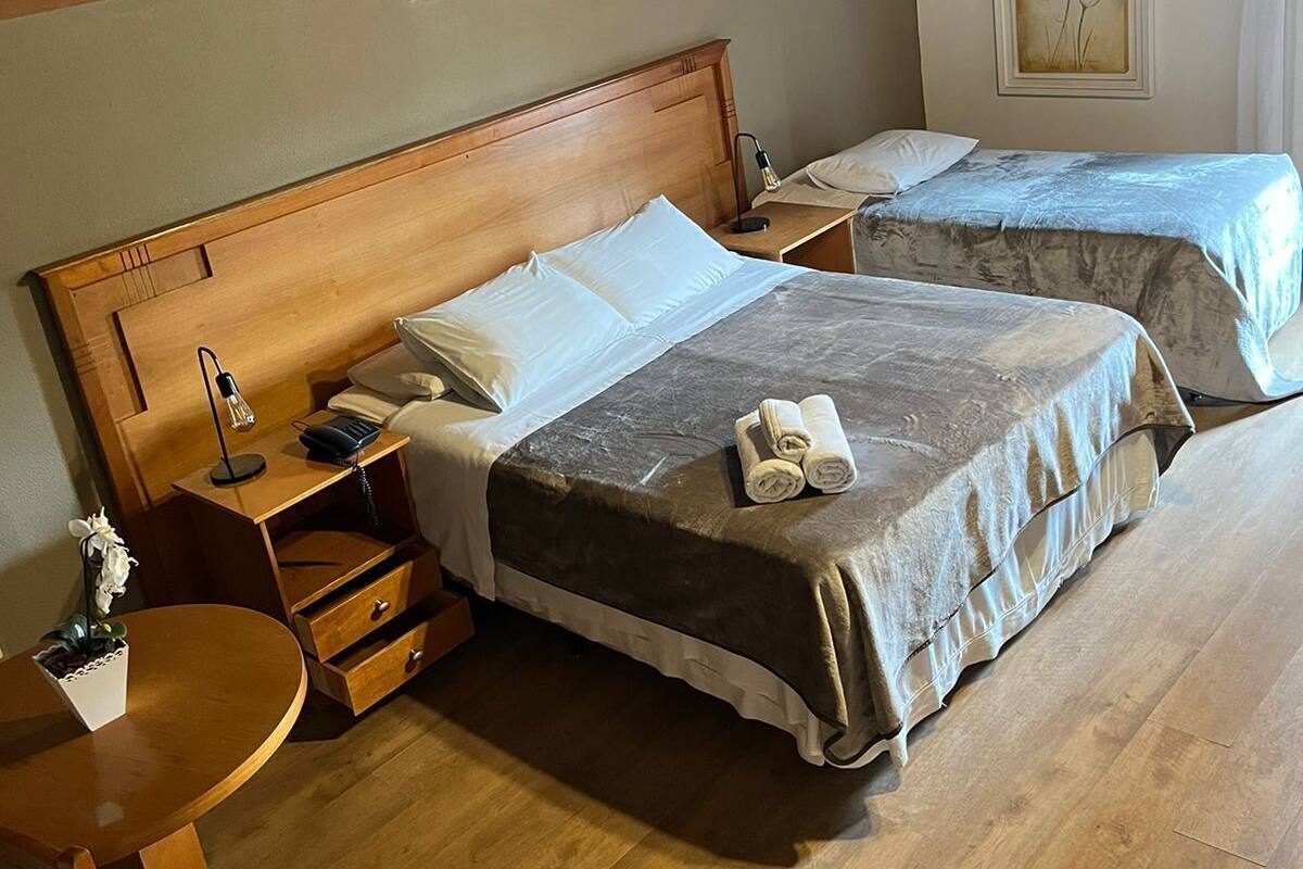 Habitación de hotel con dos camas, cabeceros de madera, un escritorio con una silla y un cuadro en la pared.