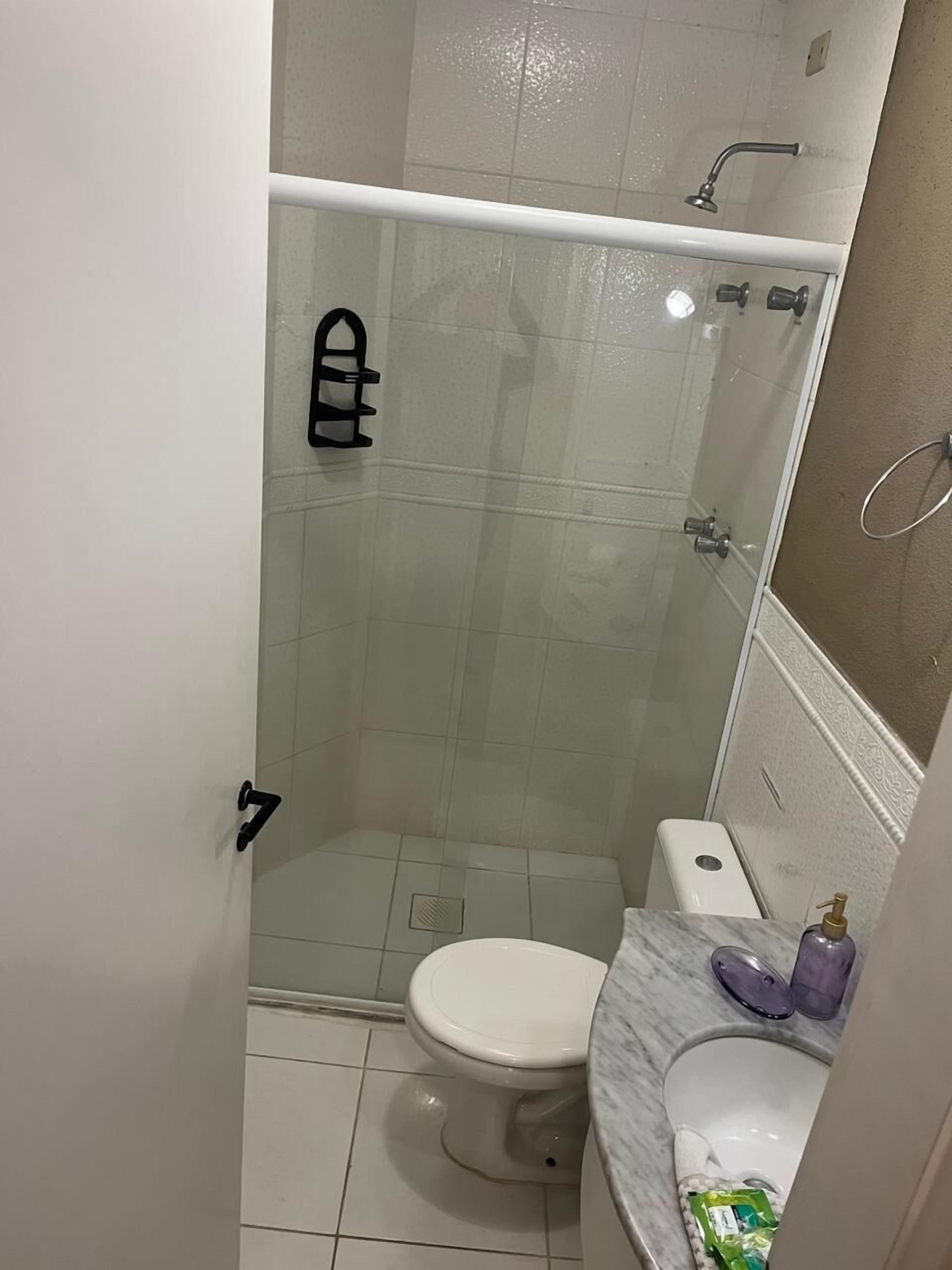 Egy kis fürdőszoba, amelyben WC, zuhanyzó és márvány mosdókagyló található.