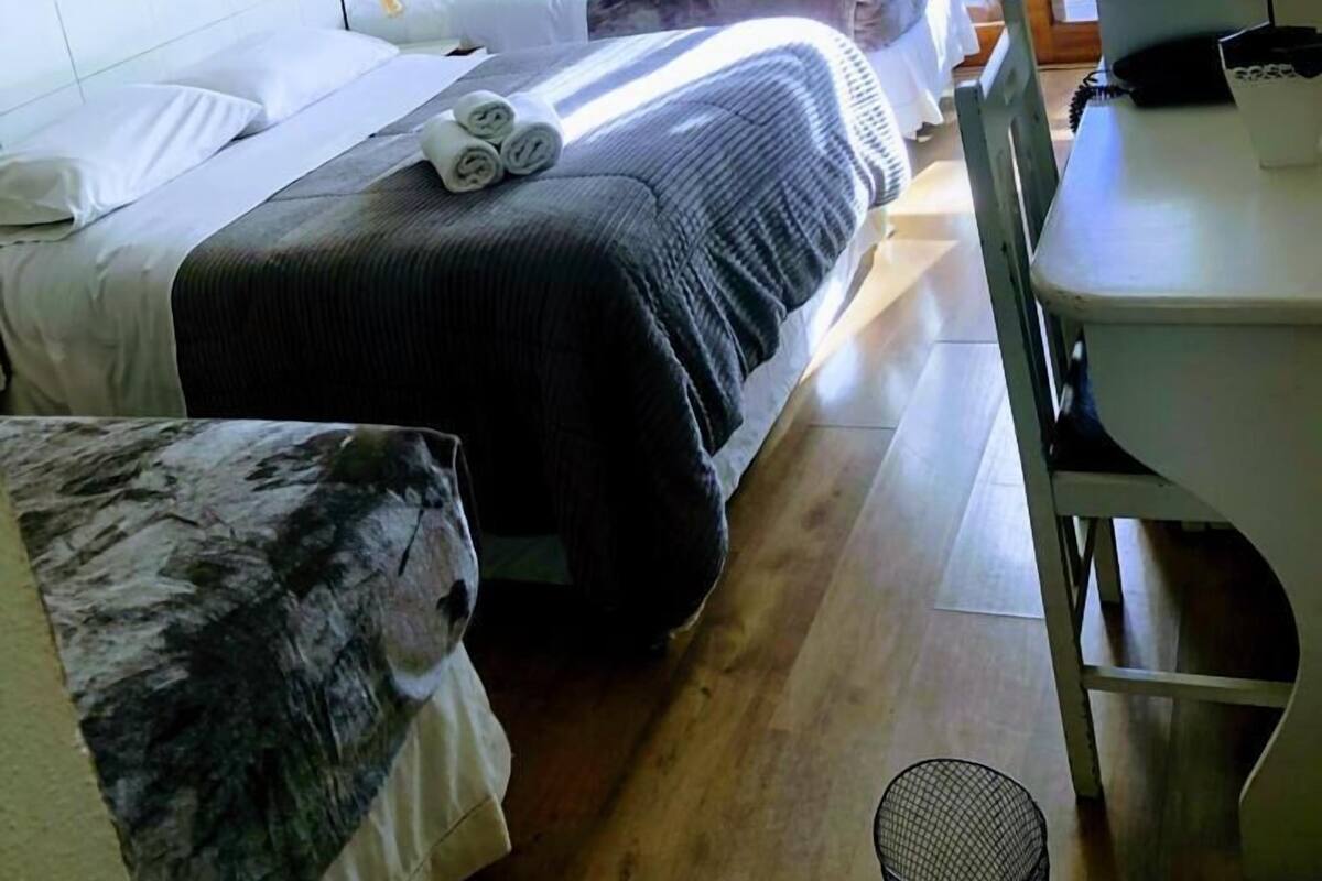 Habitación de hotel con dos camas, un escritorio y una silla.