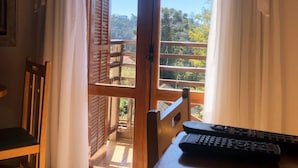 A room with a wooden table, a chair, and a view through a glass door to an outdoor balcony. - Pousada Condado Brasileiro (Campos do Jordão)