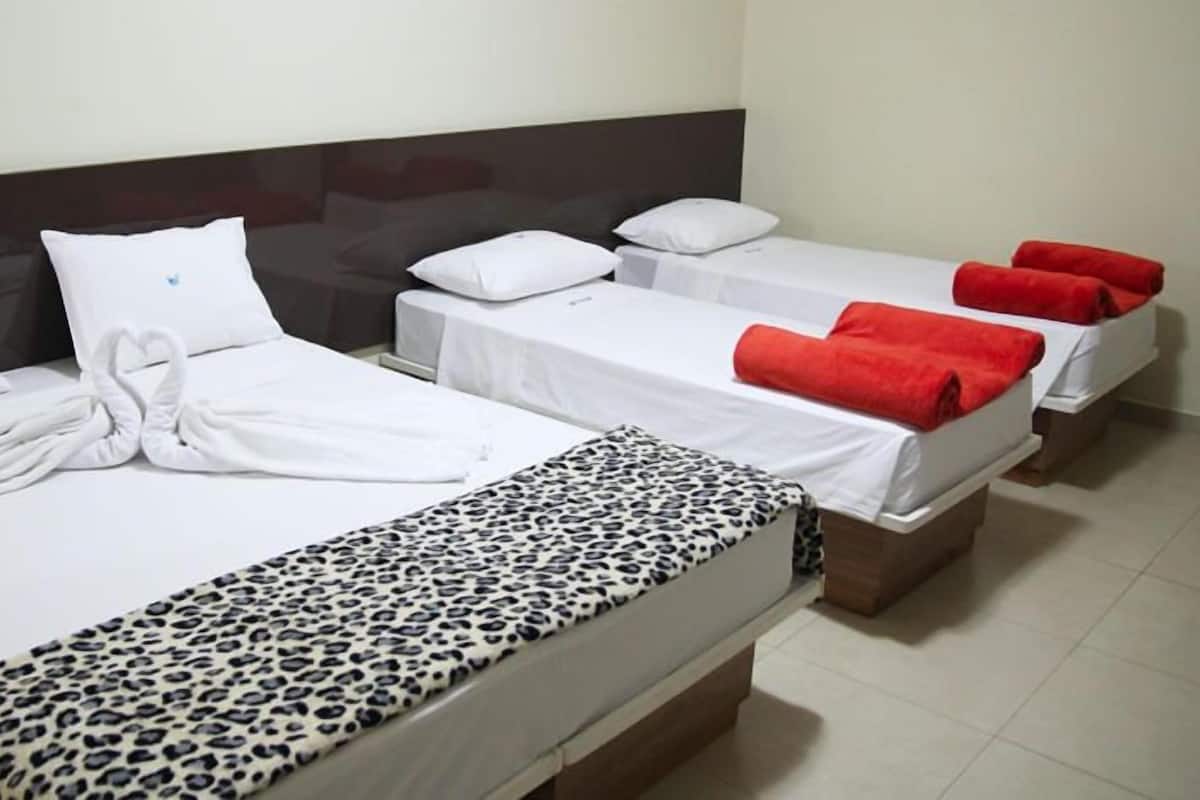 A hotel room with two beds, one with a leopard print bedspread and the other with red towels.