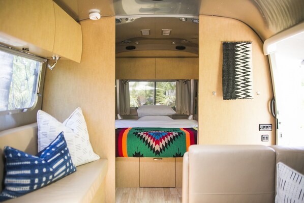 Un intérieur de camping-car compact comprenant un lit, un coin salon et une fenêtre.