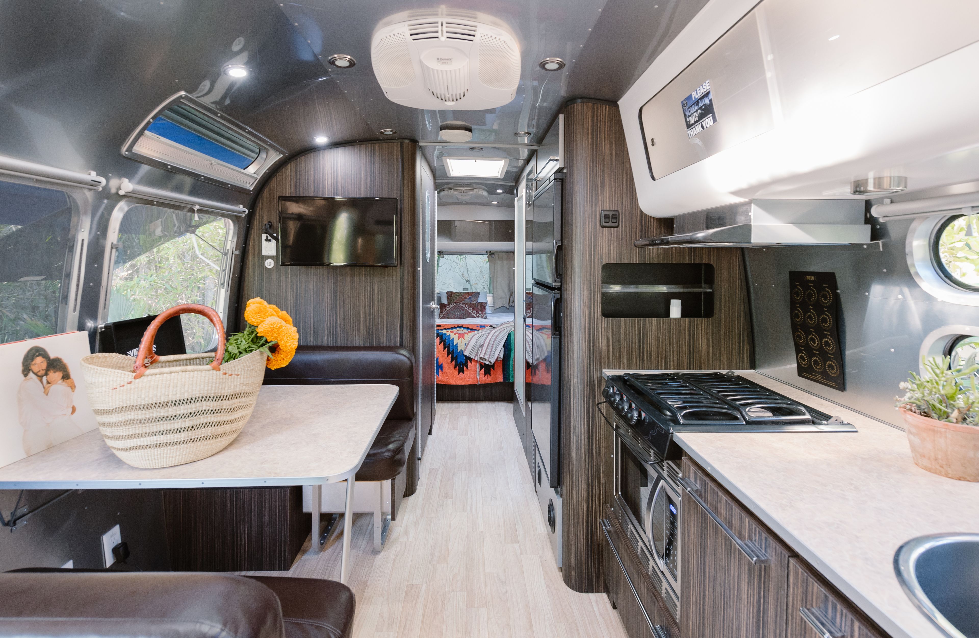 A compact RV interior with a kitchenette, a dining area, and a small living space.