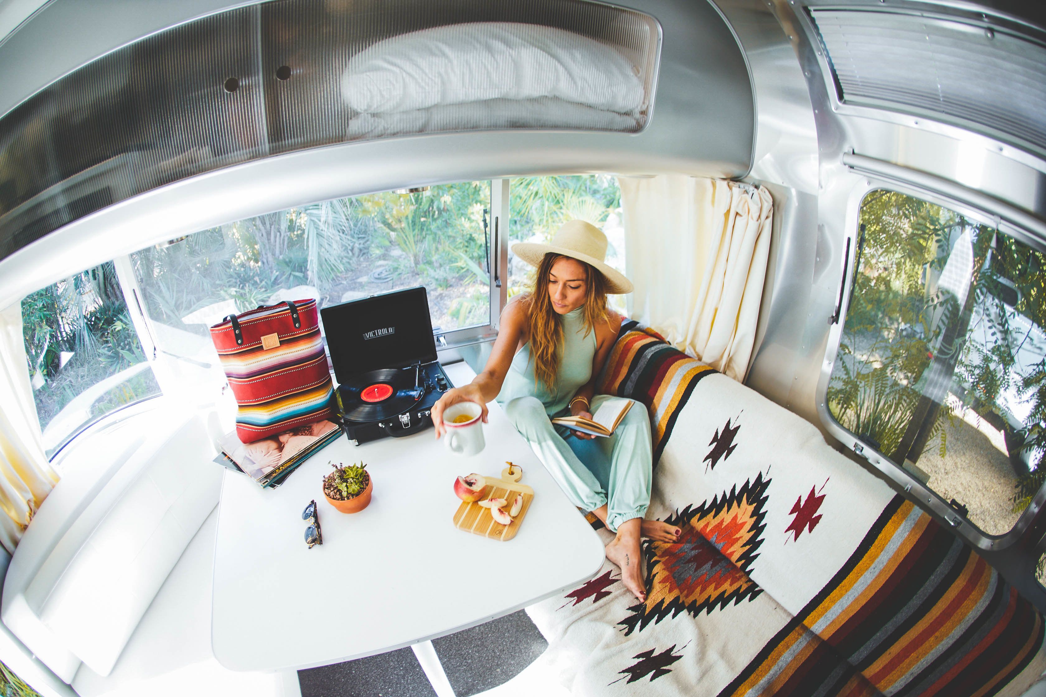A cozy interior with a sofa, a table with a laptop, a red suitcase, and a small plant.