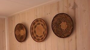 Una habitación de hotel con pared de madera, una cama con ropa blanca y tres platos decorativos en la pared.