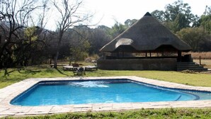 Una piscina con una estructura cubierta de paja cerca.