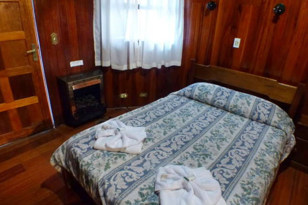 A wooden-paneled room with a bed, a small heater, and a door.