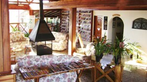 Ein gemütliches Wohnzimmer mit Kamin, einem blumigen Sofa und Bücherregalen voller Bücher.