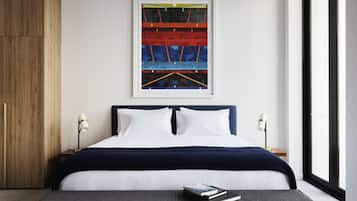 A modern bedroom with a large bed, a framed abstract painting, and a nightstand with a lamp.