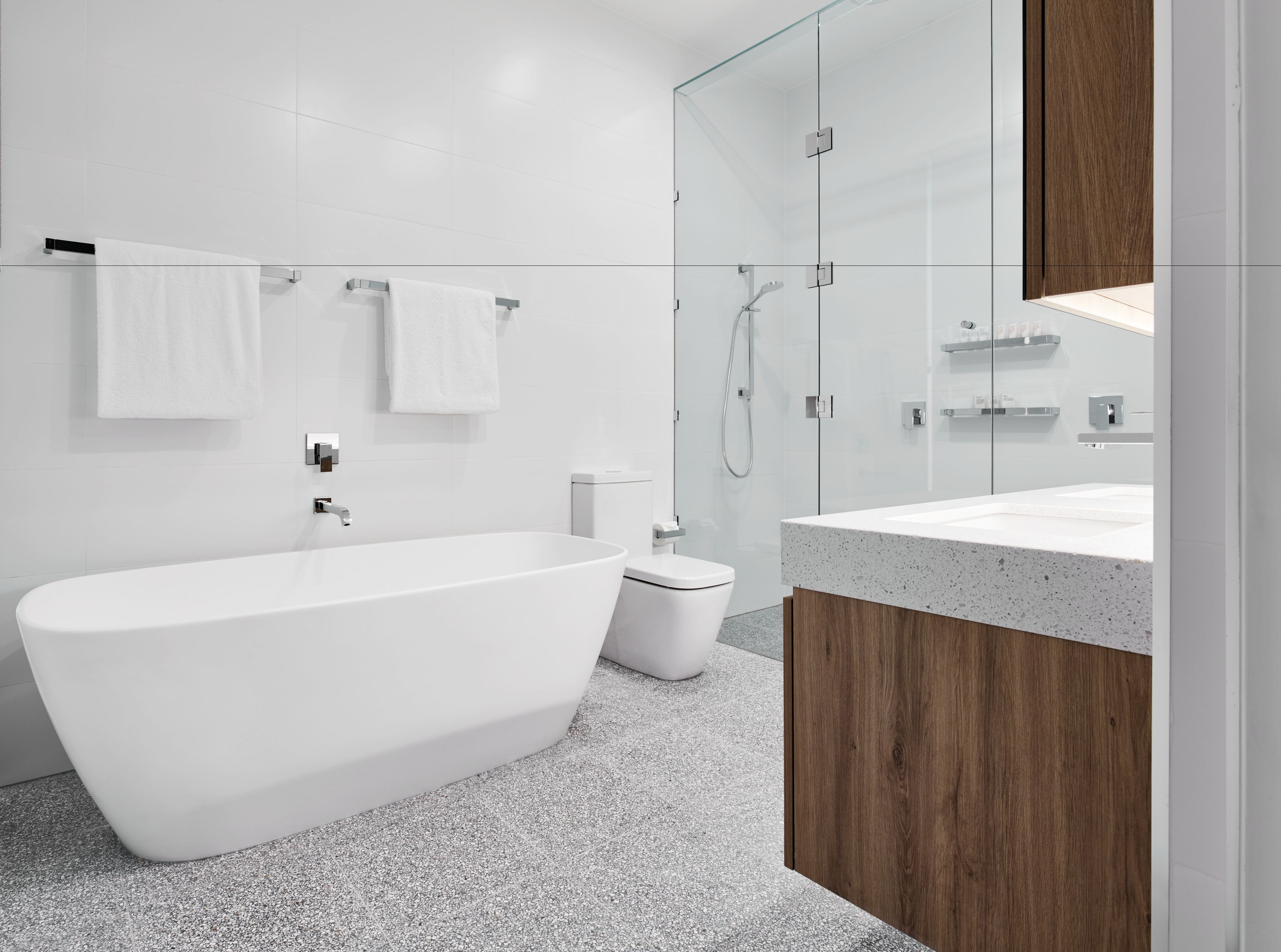 A modern bathroom with a freestanding bathtub, a glass-enclosed shower, and a wooden vanity.