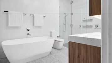 A modern bathroom with a freestanding bathtub, a glass-enclosed shower, and a wooden vanity.