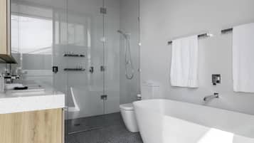 Ein modernes Badezimmer mit einer Glaskabine, einer freistehenden Badewanne und einem WC.