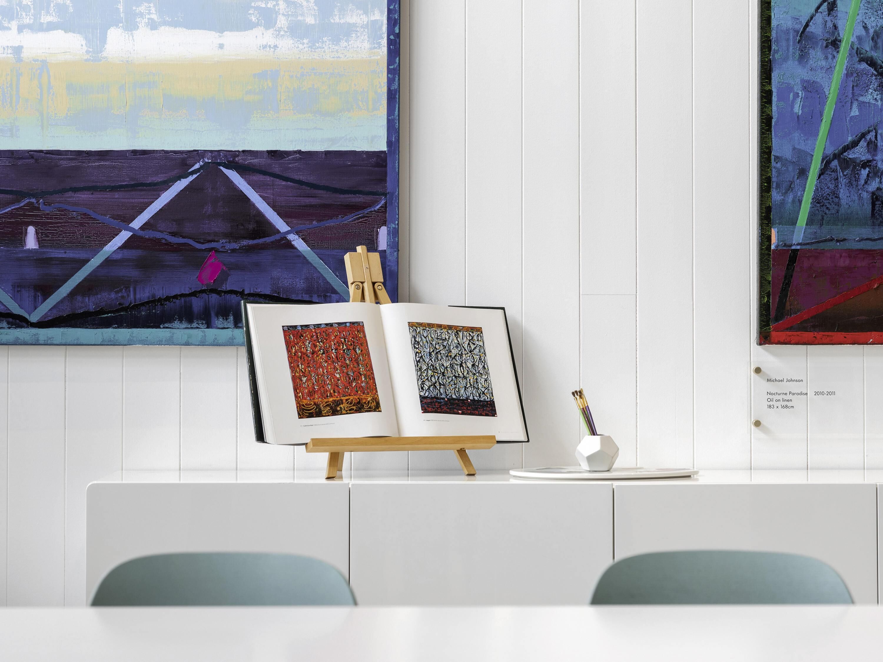 A room with a whiteboard, a framed artwork, and a small easel with an open book.
