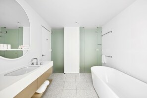 A modern bathroom with a white sink, a large mirror, a bathtub, and green walls. - The Johnson Brisbane - Art Series (Spring Hill)