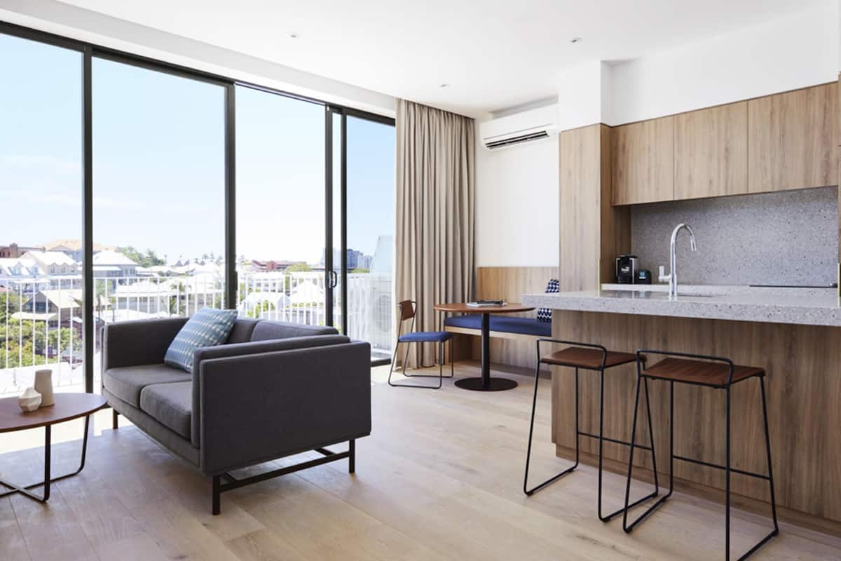 Un apartamento moderno con un ventanal grande, un sofá, un comedor y una cocina.