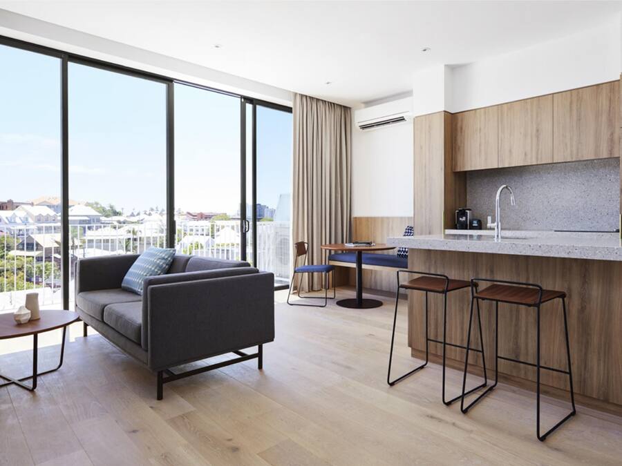 Um apartamento moderno com uma janela ampla, um sofá, uma sala de jantar e uma cozinha.