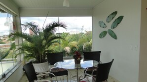 Un coin repas avec une table ronde, quatre chaises, une plante en pot et une vue sur la verdure à l’extérieur.