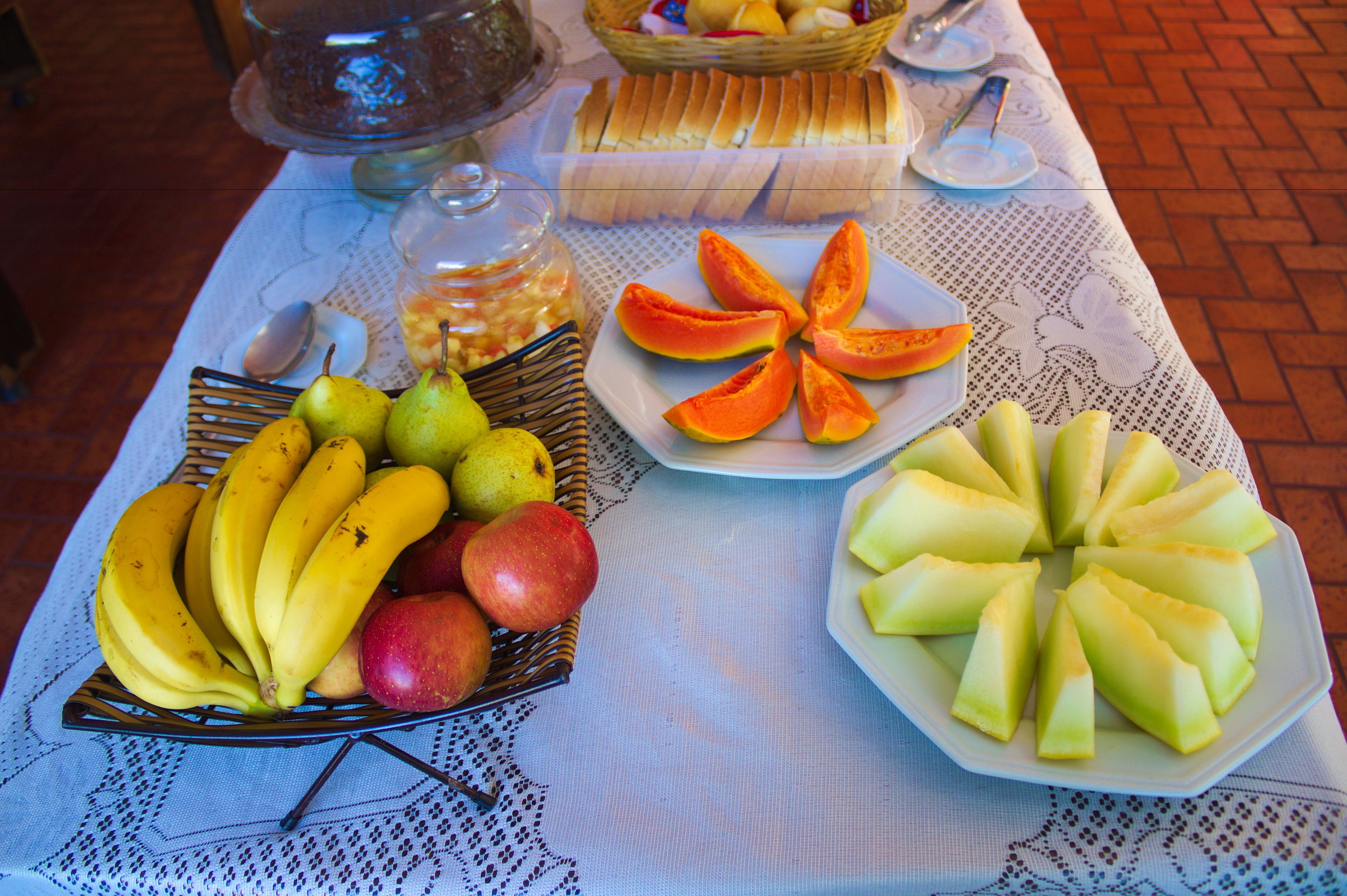 Una mesa con una composición de frutas que incluye plátanos, manzanas y papaya en rodajas.